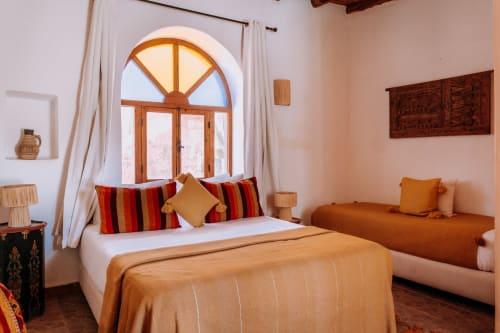 Habitación Deluxe Étnica en el hotel Eucalyptus en Essaouira con ventana arqueada, almohadas a rayas y decoración marroquí tradicional