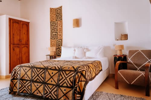 Dormitorio Deluxe de estilo étnico en Hotel Eucalyptus Essaouira con manta de patrón geométrico, puerta de madera y decoración marroquí tradicional