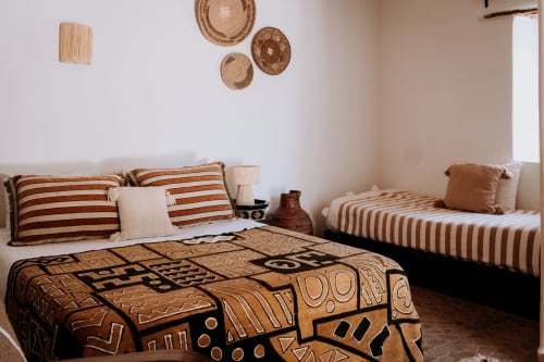 Chambre de style ethnique à l'Hôtel Eucalyptus Essaouira avec literie rayée, décoration murale en osier et touches marocaines traditionnelles