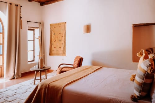 Habitación de estilo étnico en el hotel Eucalyptus Essaouira con muebles de madera, acentos de terracota y tapiz mural tradicional