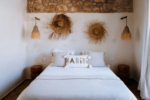 Boheme Supérieur bedroom at Eucalyptus Ethnic hotel in Essaouira with white bed, decorative straw hats and woven pouches