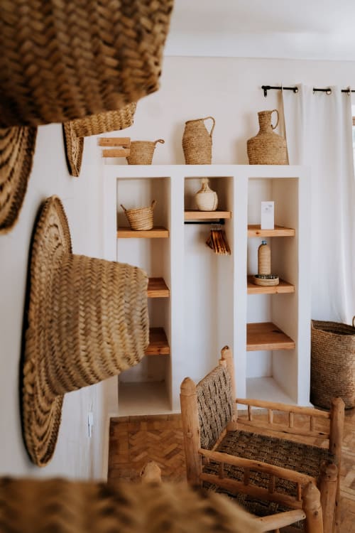Bohemian bedroom at Eucalyptus Ethnic hotel with woven baskets, white shelving, wooden bed frame, and natural décor in