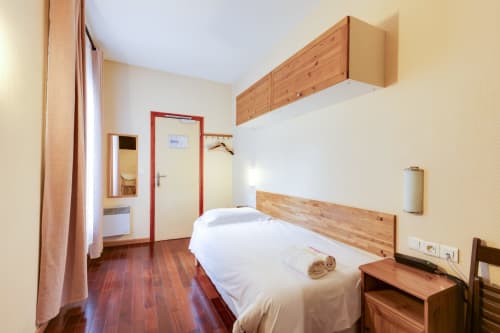 Chambre studio à la Résidence Molière Montrouge avec lit, tête de lit en bois, kitchenette et équipements modernes
