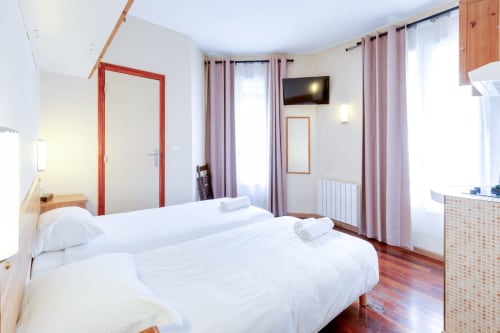 Chambre moderne à la Résidence Molière Montrouge avec lits jumeaux, chambranle rouge, télévision et rideaux roses