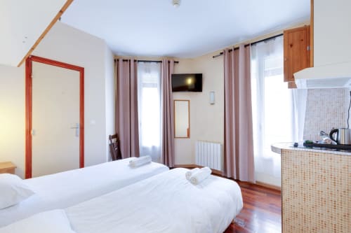 Chambre studio à la Résidence Molière Montrouge avec literie blanche, kitchenette, TV et rideaux roses