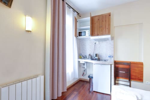 Kitchenette du studio à la Residence Moliere Montrouge avec meubles en bois, électroménagers blancs et parquet