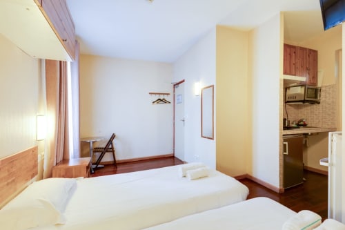 Chambre studio à la Résidence Molière Montrouge avec deux lits, kitchenette et équipements modernes