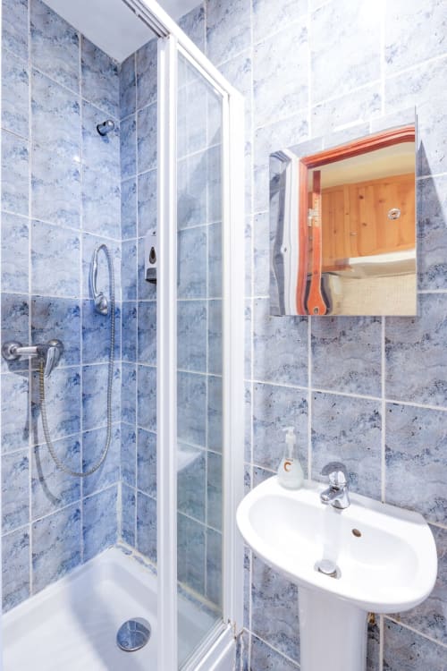 Salle de bains moderne à la Résidence Molière Montrouge avec carrelage bleu, douche, lavabo blanc et miroir