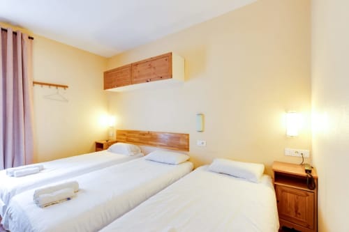 Deux lits jumeaux dans une chambre studio jaune vif à l'Hôtel Résidence Molière, Montrouge, avec mobilier en bois et équipements modernes