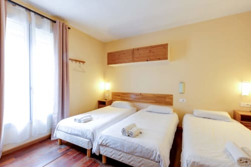 Chambre lumineuse avec lits jumeaux, mobilier en bois et murs jaunes à la Résidence Molière Montrouge