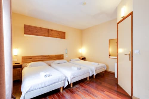 Deux lits jumeaux dans une chambre studio de l'hôtel Résidence Molière Montrouge, avec mobilier en bois et parquet