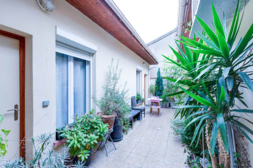 Terrasse de la Résidence Molière Montrouge avec plantes en pots, feuillage vert et portes aux volets bleus