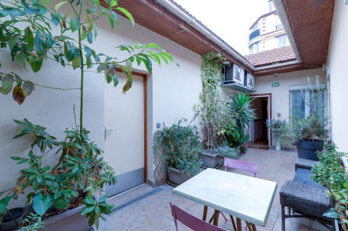 Cour intérieure du studio à Montrouge avec plantes en pot, table blanche, sièges et murs couverts de lierre à la Résidence Molière
