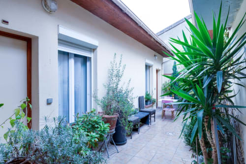 Terrasse commune de la Résidence Molière Montrouge avec plantes en pots, sièges et portes vitrées bleues