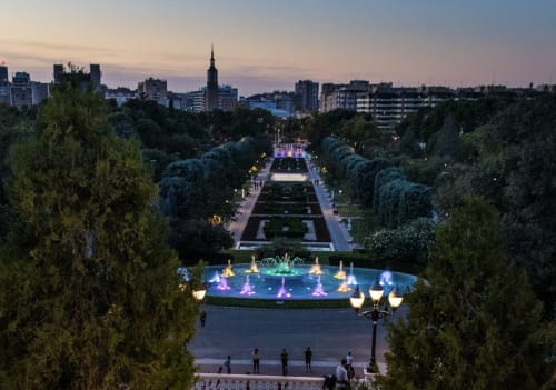 Fuente iluminada y jardines formales en Zaragoza al atardecer, cerca del Hostal Zaragoza Centro