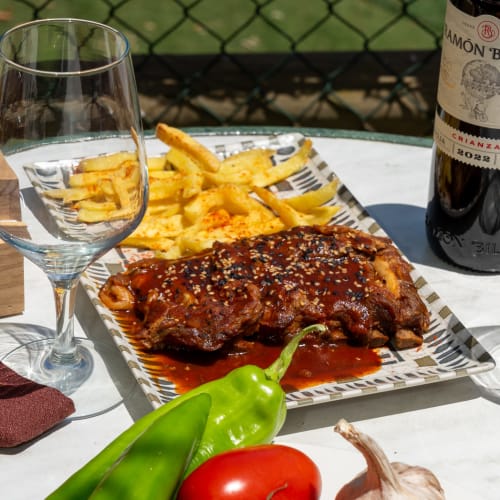 Gegrilltes Fleisch mit Sesamkörnern, Pommes und Wein im Restaurant Balcón De Los Montés in Colmenar