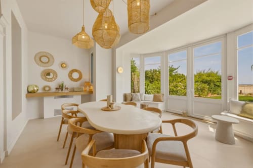 Salle à manger contemporaine aux Suites Du Port à Arcachon avec table ovale, chaises en bois et grandes fenêtres donnant sur les jardins.