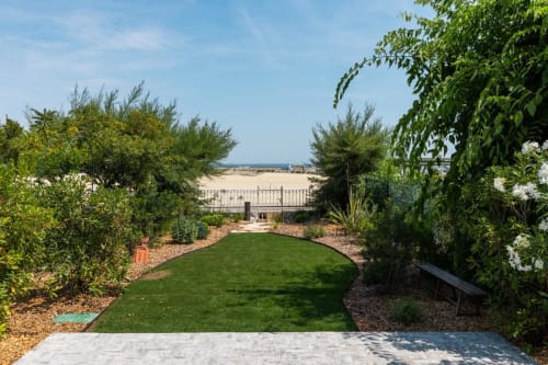 Jardin aménagé avec pelouse verdoyante et arbustes fleuris aux Suites Du Port, Arcachon, vue sur la plage