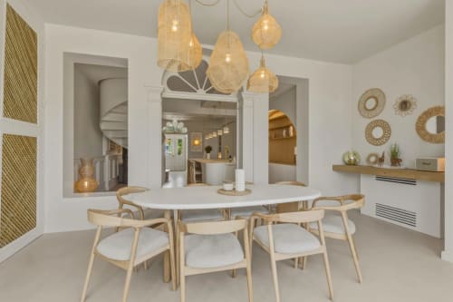 Salle à manger contemporaine aux Suites Du Port à Arcachon avec table ronde, chaises en bois et luminaires suspendus tressés