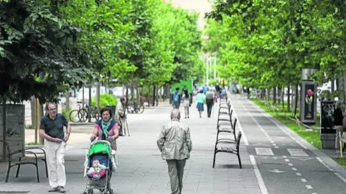 Calle peatonal arbolada en Zaragoza con paseantes y bancos, cerca del Hostal Zaragoza Centro