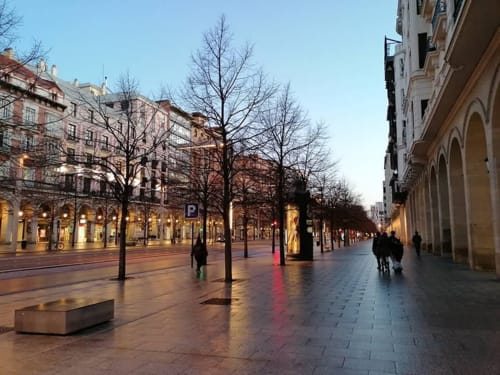 Plaza peatonal mojada del Hostal Zaragoza Centro con edificios históricos porticados, árboles desnudos y farolas nocturnas