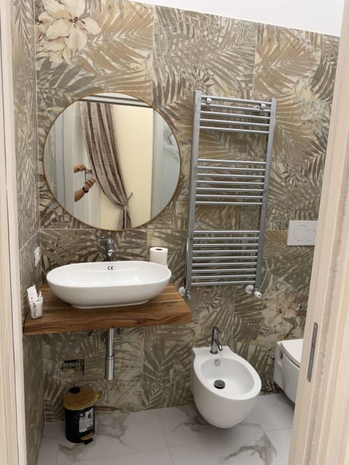 Bagno moderno con carta da parati tropicale, lavabo ovale bianco, specchio rotondo e scaldasalviette presso Zappy Domus B&B a Taranto