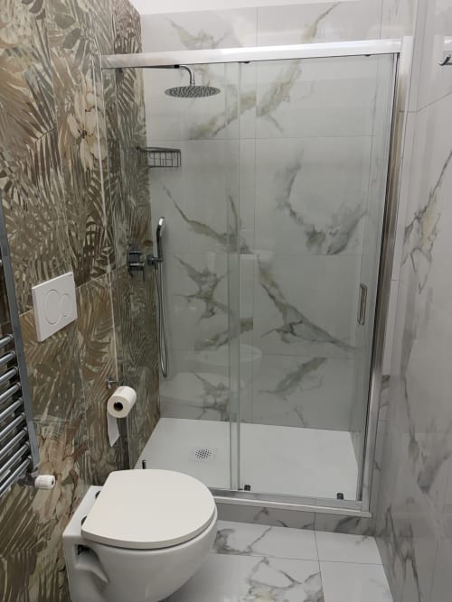 Bagno moderno con cabina doccia effetto marmo, toilette bianca e parete con piastrelle decorative presso Zappy Domus B&B a Taranto