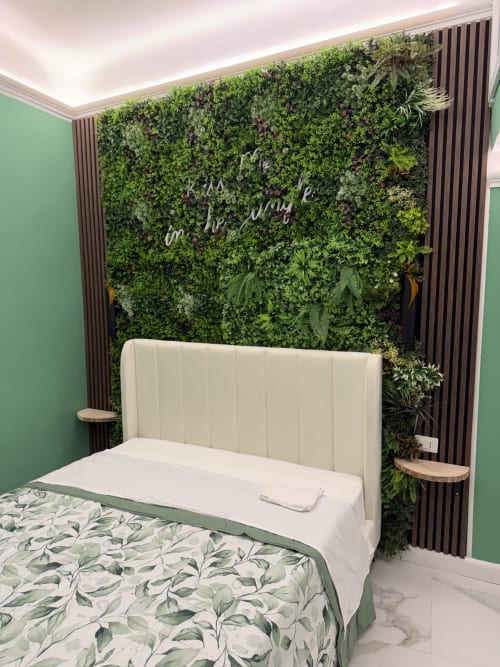 Camera moderna con testata crema, pareti verdi e sfondo botanico con testo al neon presso Zappy Domus a Taranto