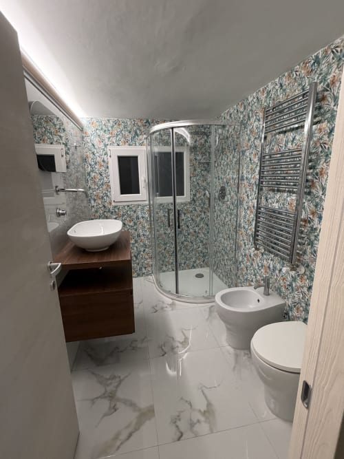 Bagno moderno a Zappy Domus a Taranto con pavimento in marmo, carta da parati floreale, box doccia e doppio lavabo
