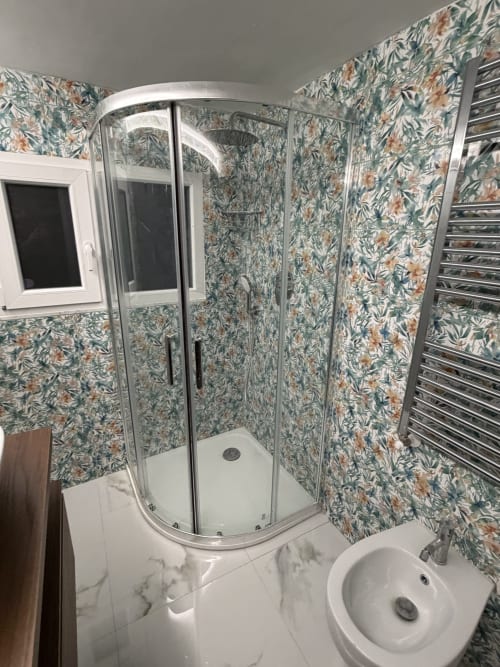 Bagno moderno dello Zappy Domus B&B a Taranto con box doccia in vetro curvo, sanitari bianchi e decor floreale
