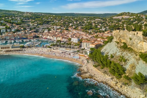 Aerial view of Villefranche-sur-Mer beach with turquoise waters, red-roofed buildings, and limestone cliffs