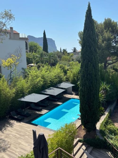 Villa Annette's pool terrace with blue water, loungers, cypress trees, and mountain views in French countryside