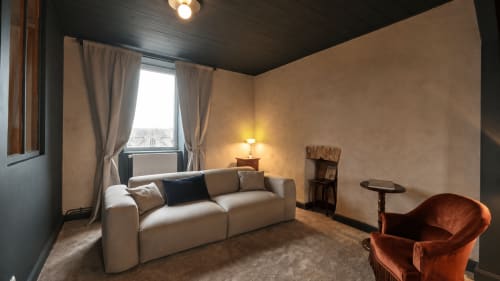 Cozy living room at La Maison 1903 B&B in Trévou-Tréguignec with beige sofa, terracotta chair, and dark wooden ceiling
