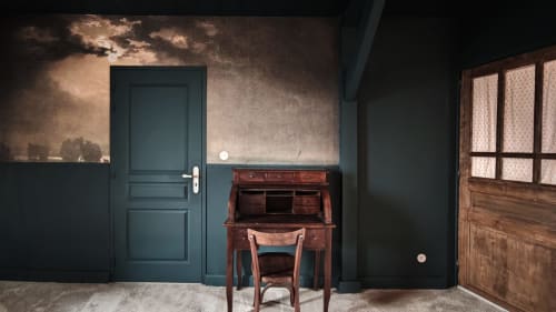 Chambre 1903 de La Maison avec bureau ancien, chaise, fresque murale dramatique, porte turquoise et armoire en bois.