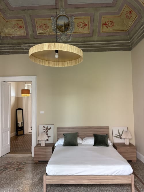 Modern bedroom at Sicily In Home hotel in Catania with wooden bed, green pillows, pendant light, and ornate ceiling frescoes