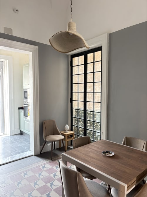 Sala da pranzo moderna presso Sicily In Home con tavolo in legno, lampada a sospensione, finestre con cornici nere e vista sulla città di Catania