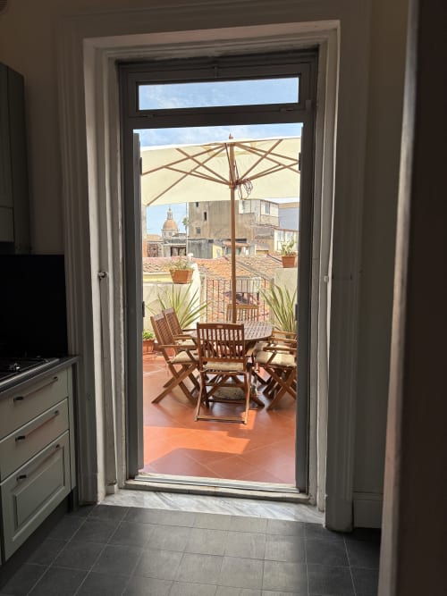 Terrazza panoramica con arredamento in legno e ombrellone con vista sulla città di Catania in questa casa vacanza siciliana