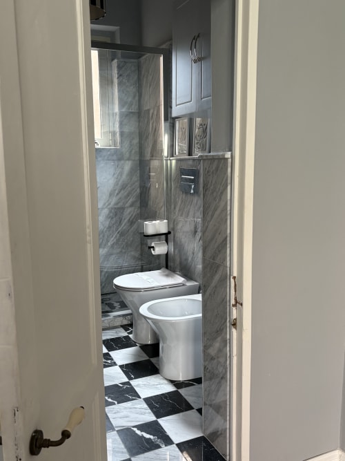 Bagno moderno con rivestimenti effetto marmo, wc e bidet bianchi, doccia walk-in con box in vetro all'hotel Sicily In Home