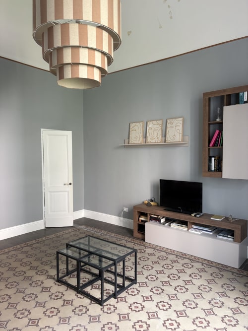 Moderna sala da soggiorno a Sicily In Home Catania con TV, arredamento in legno, lampada sospesa a righe e pavimento a motivi geometrici