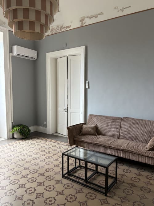 Soggiorno moderno dell'hotel Sicily In Home a Catania con divano rigato, tavolino nero e pareti grigie
