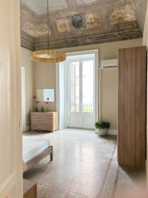 Camera da letto moderna a Catania con mobili in legno, affascinante affresco al soffitto, lampada sospesa e accesso al balcone