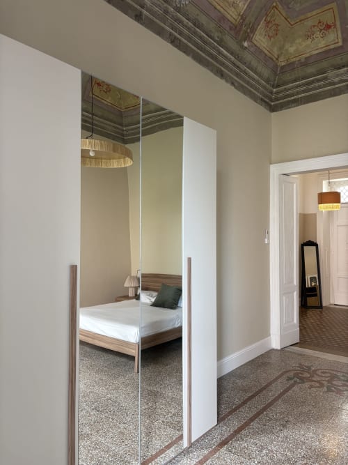 Camera da letto moderna con armadio a specchi e letto in legno presso l'hotel Sicily In Home a Catania
