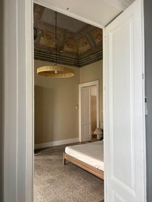 Camera da letto spaziosa dell'hotel Sicily In Home a Catania con soffitto ornamentale, lampadario a sospensione, letto in legno e pareti beige