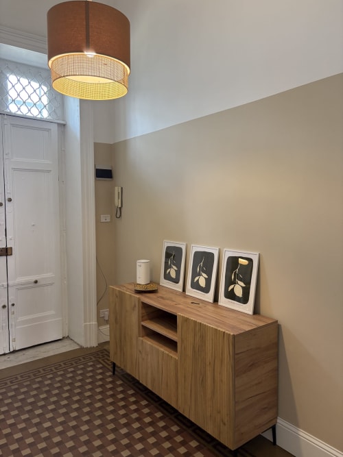 Corridoio moderno nell'appartamento di Catania con mobile in legno, arte botanica incorniciata, lampada a sospensione e porte bianche