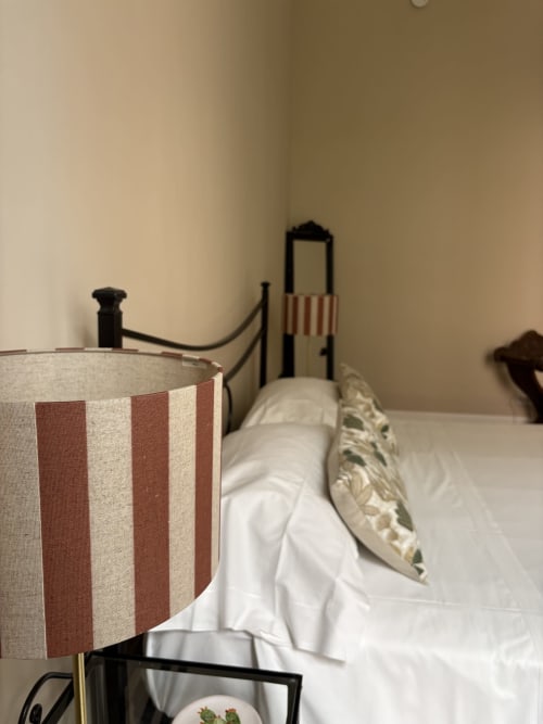 Camera da letto con lampada a righe rosse e bianche, biancheria bianca e cuscino decorativo presso l'hotel In Home, Catania
