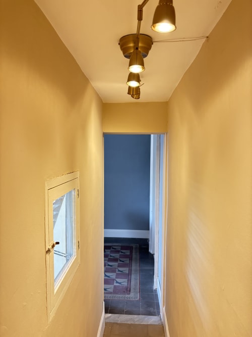Luminoso corridoio giallo con luci in ottone a soffitto che conduce alla camera da letto dell'In Home hotel, Catania, Sicilia