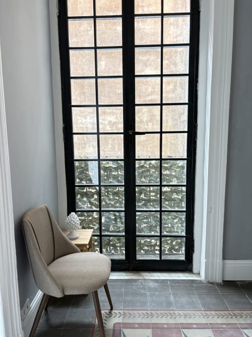 Poltrona beige accanto a porte-finestre con cornice nera e vista sulla città di Catania, camera dell'hotel In Home in Sicilia