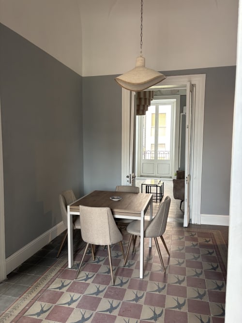 Moderna sala da pranzo dell'hotel Sicily In Home a Catania con tavolo in legno, sedie beige, lampada a sospensione e dettagli siciliani