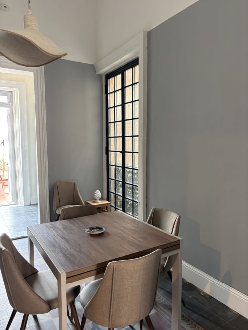 Sala da pranzo moderna con tavolo in legno, sedie beige, lampada a sospensione e finestra panoramica con vista su Catania