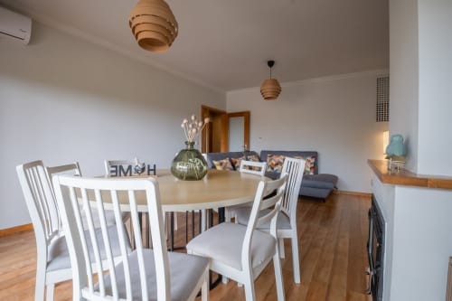 Moderner Essbereich mit rundem Tisch, weißen Stühlen und Wohnzimmer im EcoHost-Apartment in Porto